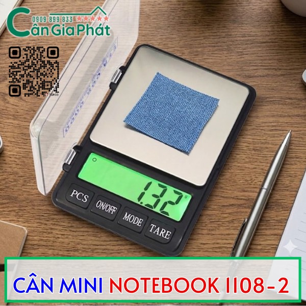 Cân điện tử mini Notebook 1108 2 màn hình xanh đang cân miếng vải nhỏ trên bàn làm việc
